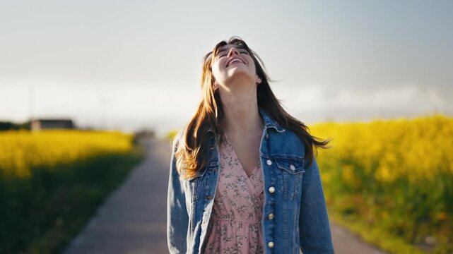 Smiling woman strolls through blooming yellow rape fields