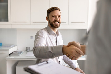 Smiling male patient handshake with therapist in clinic office