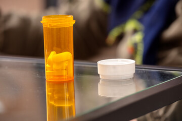 Orange Prescription Pill Bottle with White Cap on Glass Table