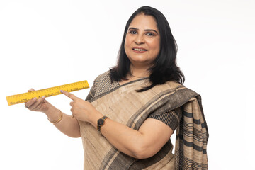 Indian school teacher showing measurement scale while standing isolated in white background. looking in front of the camera