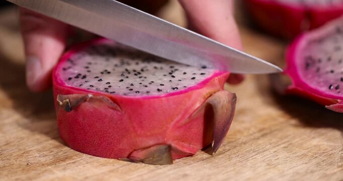 ripe red pitaya cut in half with lots of small black seeds and white soft sweet flesh inside, ripe dragon fruit with black small seeds and light flesh cut in half
