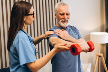 Senior man experiencing shoulder pain during physical therapy, mature patient doing exercises