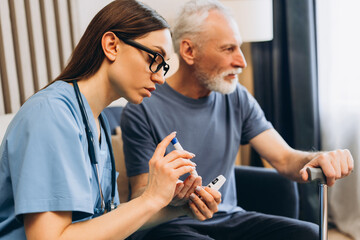 Beautiful woman, nurse checking senior man's blood sugar level sitting in living room