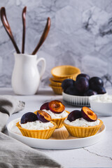 Mini tartlets with cottage cheese and plum on a plate on the table vertical view