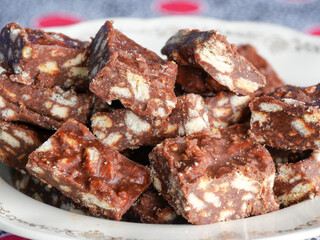 Close-up of blocks of chocolate brownie and biscuit sweets stacked on top of each other on a plate