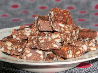 Close-up of blocks of chocolate brownie and biscuit sweets stacked on top of each other on a plate