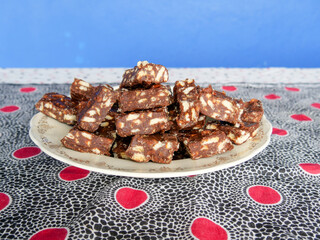 Close-up of blocks of chocolate brownie and biscuit sweets stacked on top of each other on a plate.