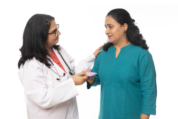 Indian Smiling doctor giving medicine to a unhealthy woman and explain her how to take the pills...