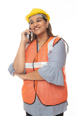 Digital India. Female constructor talking on mobile phone. Wearing hardhat and worker apron while isolated on white studio background.