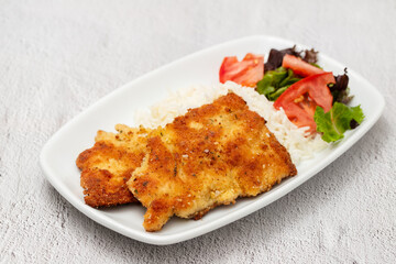 crispy breaded chicken breast with boiled rice and salad