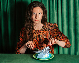 Woman in animal print cutting stack of money on plate with knife and fork