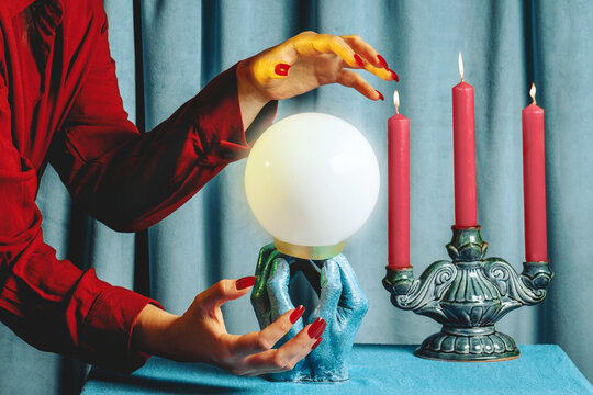 Fortune teller hands over crystal ball and candles during ritual indoors