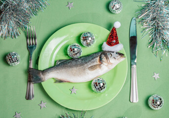 Raw fish on plate with Santa hat and festive party decorations