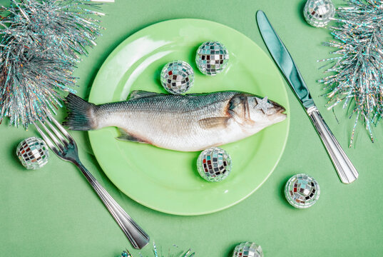 Raw fish on green plate with disco balls and festive cutlery still life