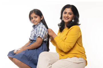 Indian mother combing to her daughter for ready to school isolated on white studio background. Concept : Mother and Daughter 