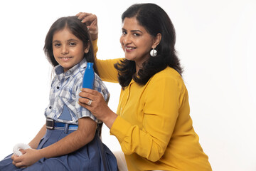 Indian mother oiling to daughter hairs on white.
Concept : Daughter Caring