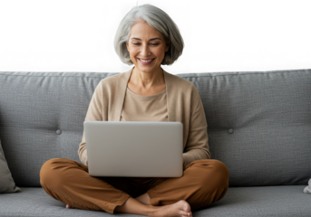 Smiling woman with gray hair using a laptop on a couch isolated on transparent background