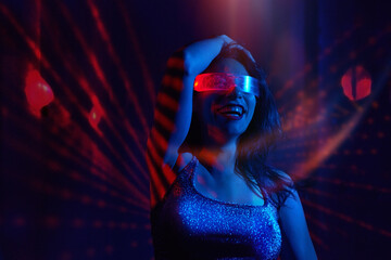 Woman dancing in nightclub with VR set and neon lighting