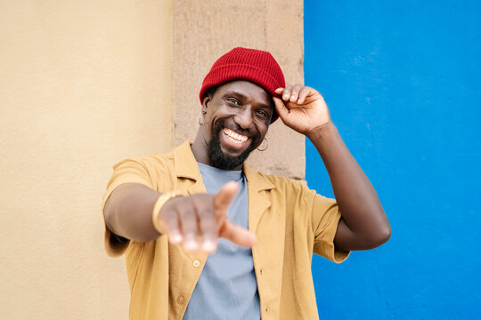 Smiling man in beanie pointing with cheerful gesture outdoors