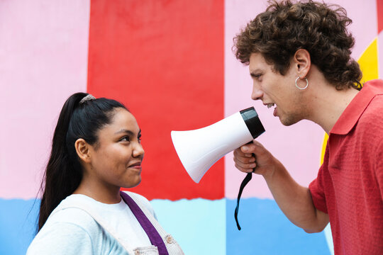 Two friends having a playful conversation with megaphone outdoors