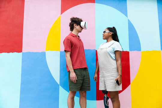 Friends interacting outdoors with virtual reality headset and prosthetic leg - Powered by Adobe