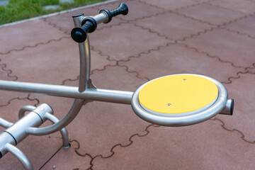 Close-up of yellow platform and handle of a playground seesaw
