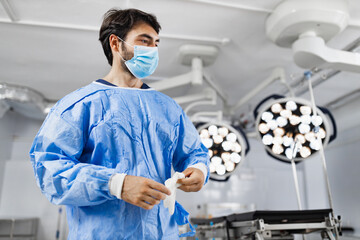 A surgeon wearing a mask and surgical gown prepares for an operation in a modern operating room.