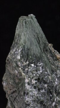 Actinolite (calcium silicate hydroxide) amphibole silicate mineral, rotating slowly against a black background. Vertical