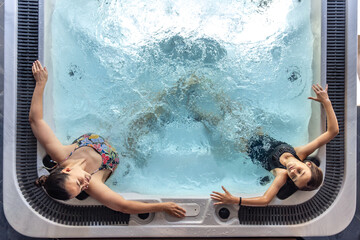 Woman and girl in hot tub mirrored pose. Shared relax moment.