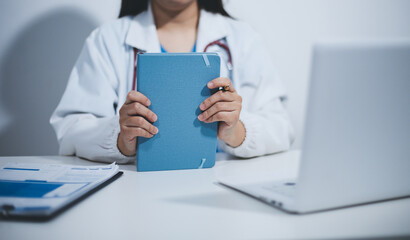 Middle aged female doctor working on laptop in doctor's room