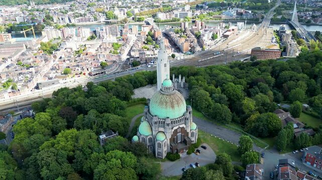 Aerial view of the Cointe Intercommunal Memorial surrounded by vibrant green trees, contrasting with the city's skyline, Li&egrave;ge, Wallonia, Belgium.