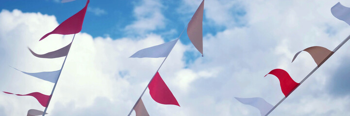 Festive ribbon of white and red triangles flags on the white clouds and blue sky background