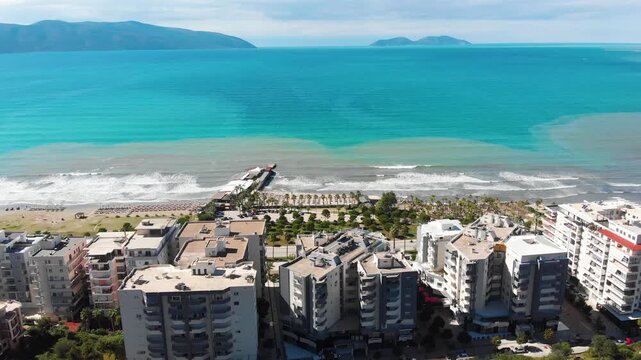 Aerial drone view of the stunning Albanian Riviera coastline, near the city of Vlora, Saranda showcasing pristine white beaches, turquoise sea water, cliffs and mountains under the Mediterranean sun.
