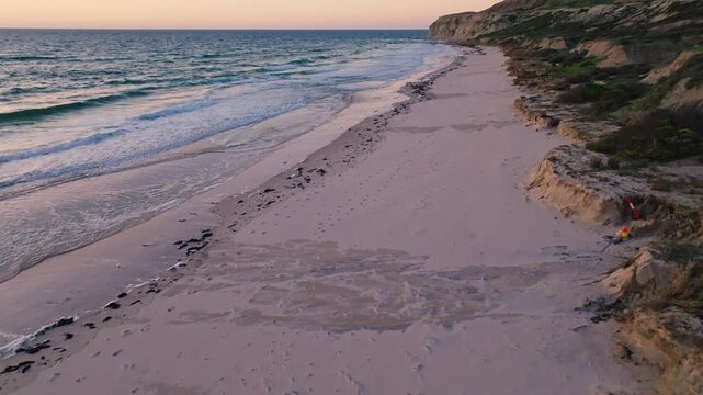 Aerial view of the beach and coastline. Soft light kisses the sand meeting the waves, Port Willunga, South Australia, Australia.