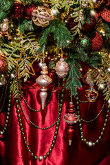 Beautiful classically decorated Christmas tree with large golden beads on a red festive velvet background, selective focus
