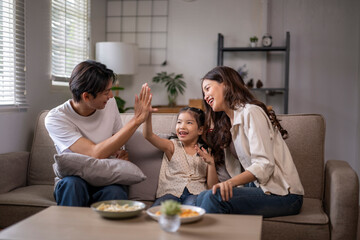Asian family giving high five on couch