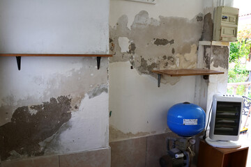 Severely Damaged Wall with Plaster Loss and Moisture Stains Caused by Rising Capillary Damp, Highly Dangerous Due to Exposed Electrical Cables 