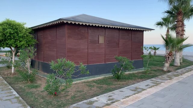 An outbuilding on the waterfront, surrounded by various plants. It's designed for use by construction workers, or available for lease as a cafe or other business.