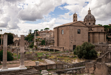 Obraz premium Ancient Roman ruins and historical buildings under dramatic cloudy sky in Rome