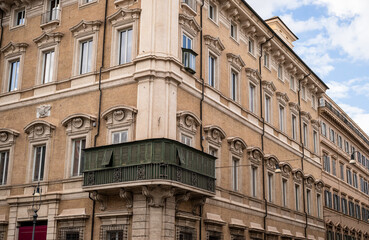 Historic European building facade with ornate windows and green enclosed balcony in Rome