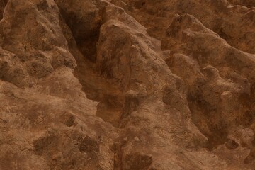 Close-up of an eroded, rugged terrain featuring warm, earthy tones. Jagged peaks and deep crevices create a dramatic, textured landscape resembling a dry, ancient surface