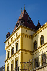 Old building castle with red tiled roof and towers in Gothic style in medieval European town. Clear blue sky. Copy space.