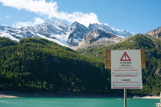 Wide panoramic view of Tre Levanne peaks above Lake Ceresole Reale in Piedmont, Italy. A clear, sunny alpine day showcasing the beauty of the Gran Paradiso mountains and the pristine natural landscape