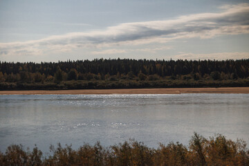 A beautiful and serene river scene showcases vibrant autumn colors against a backdrop of a clear blue sky