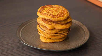 A close-up stock photo of a stack of fluffy pumpkin spice pancakes topped with syrup