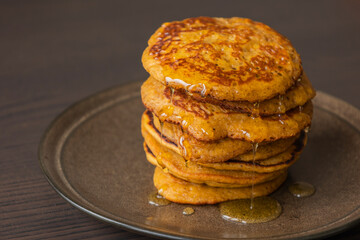 A close-up stock photo of a stack of fluffy pumpkin spice pancakes topped with syrup