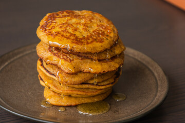 A close-up stock photo of a stack of fluffy pumpkin spice pancakes topped with syrup