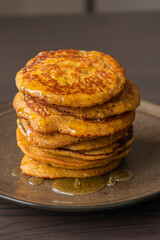 A close-up stock photo of a stack of fluffy pumpkin spice pancakes topped with syrup