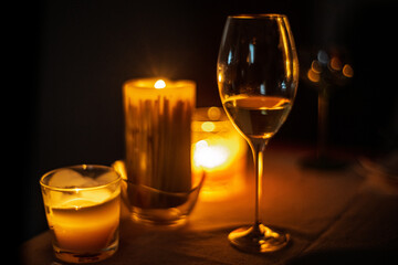 Soft candlelight casts warm reflections on white wine glass