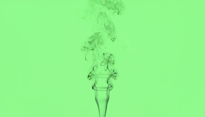 Fototapeta premium A vibrant image of smoke swirling above a unique glass, set against a striking green background, perfect for creative projects.